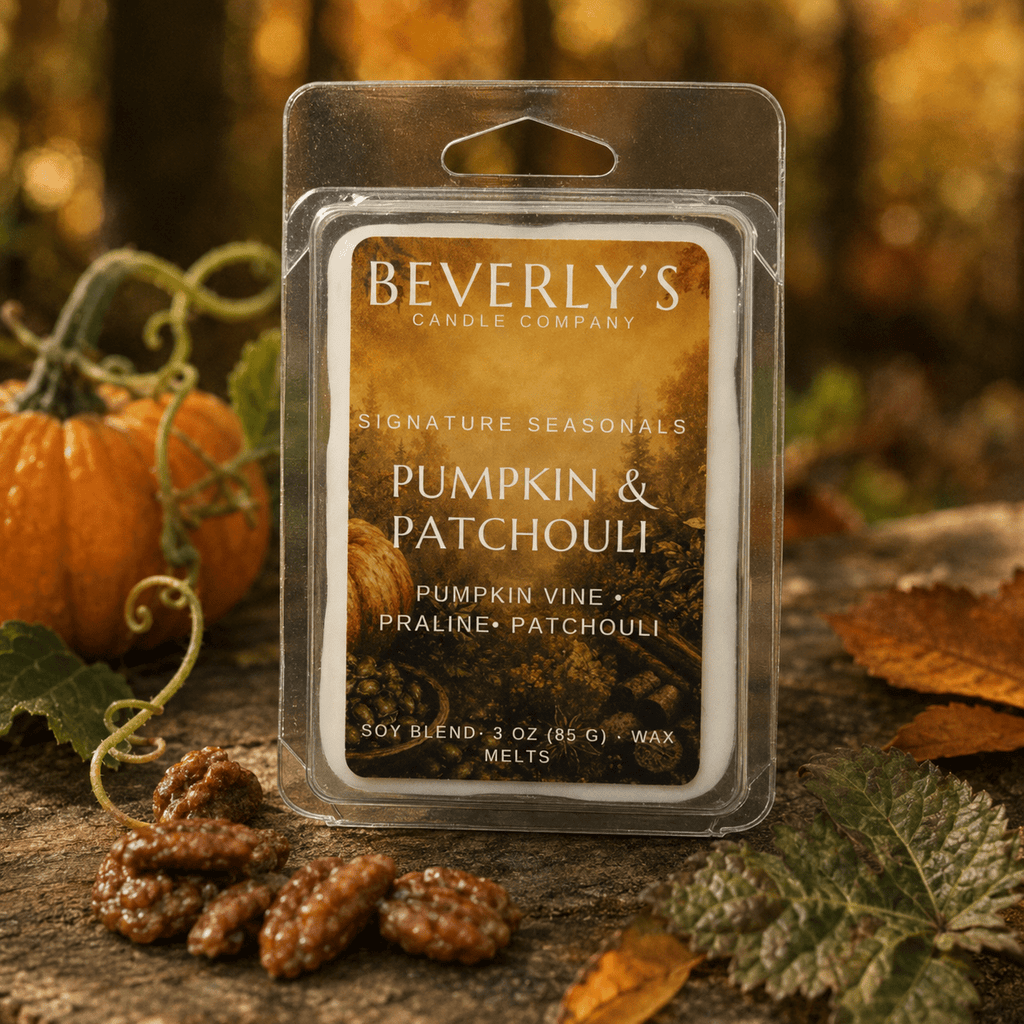 Pumpkin and Patchouli wax melt clamshell standing outdoors with pecan pralines and a small pumpkin, blurred autumn forest background